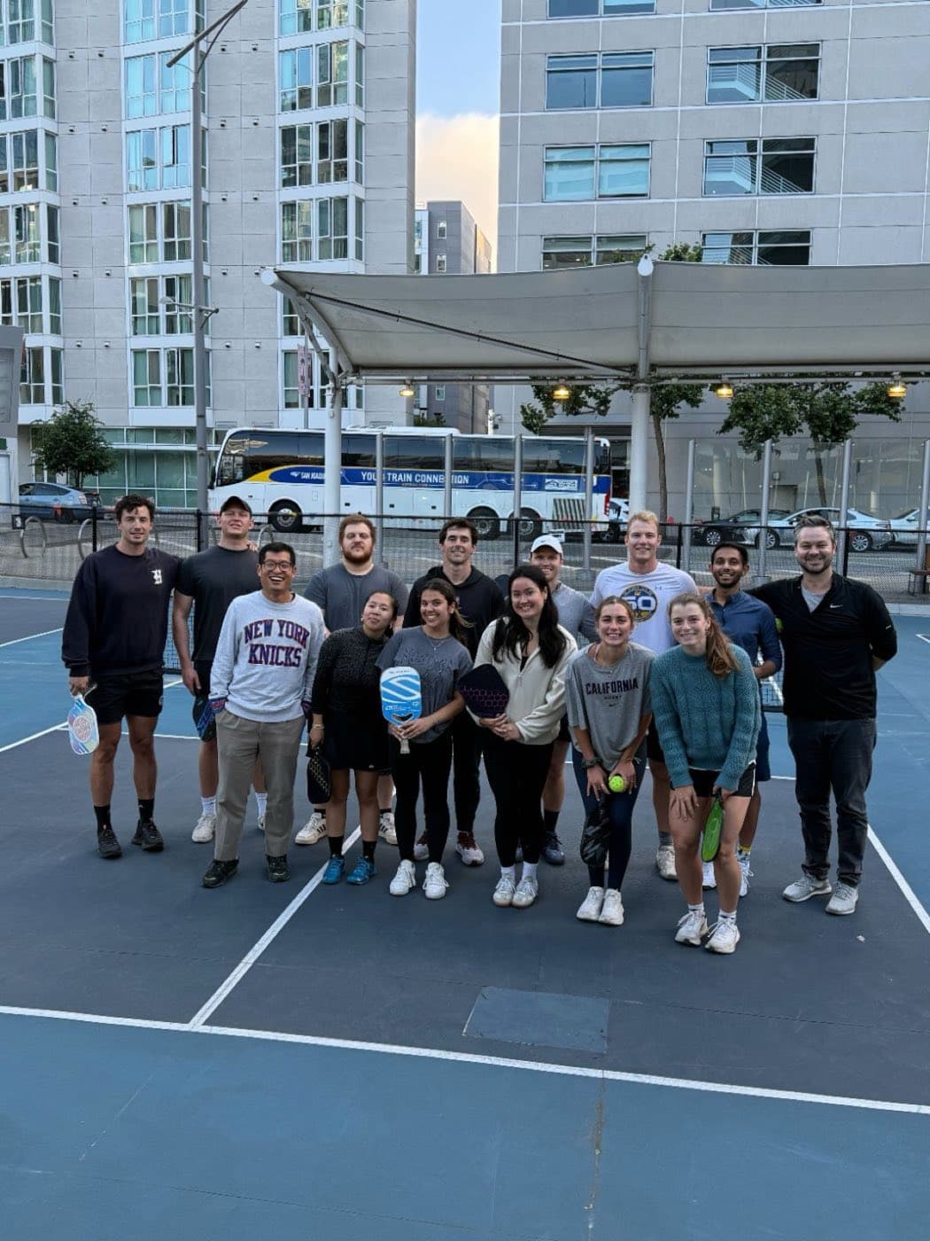 The team on a pickleball court holding paddles