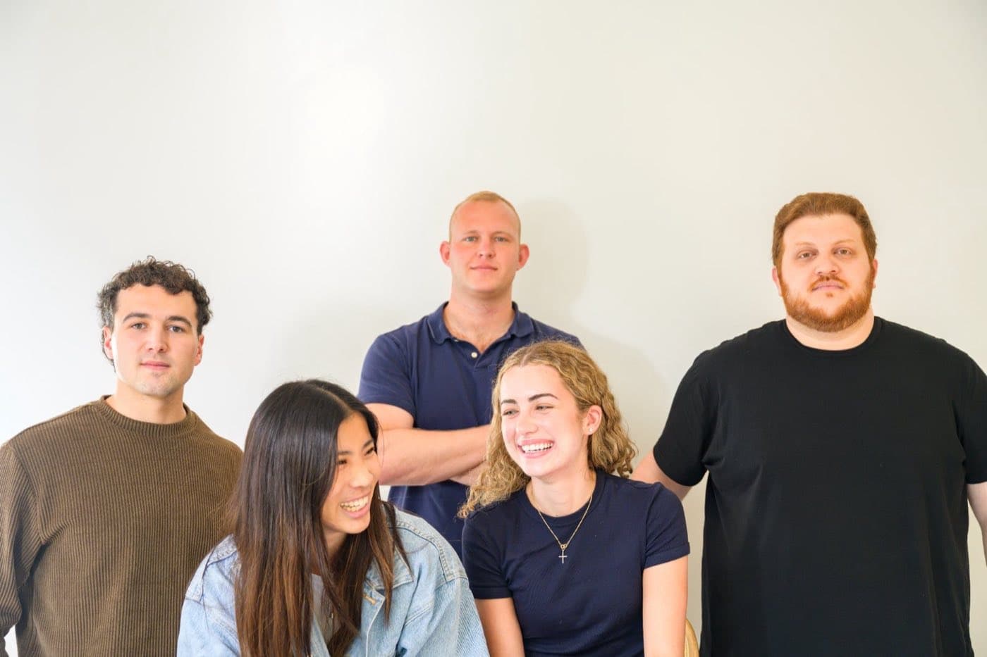 Five teammates laughing during a group portrait